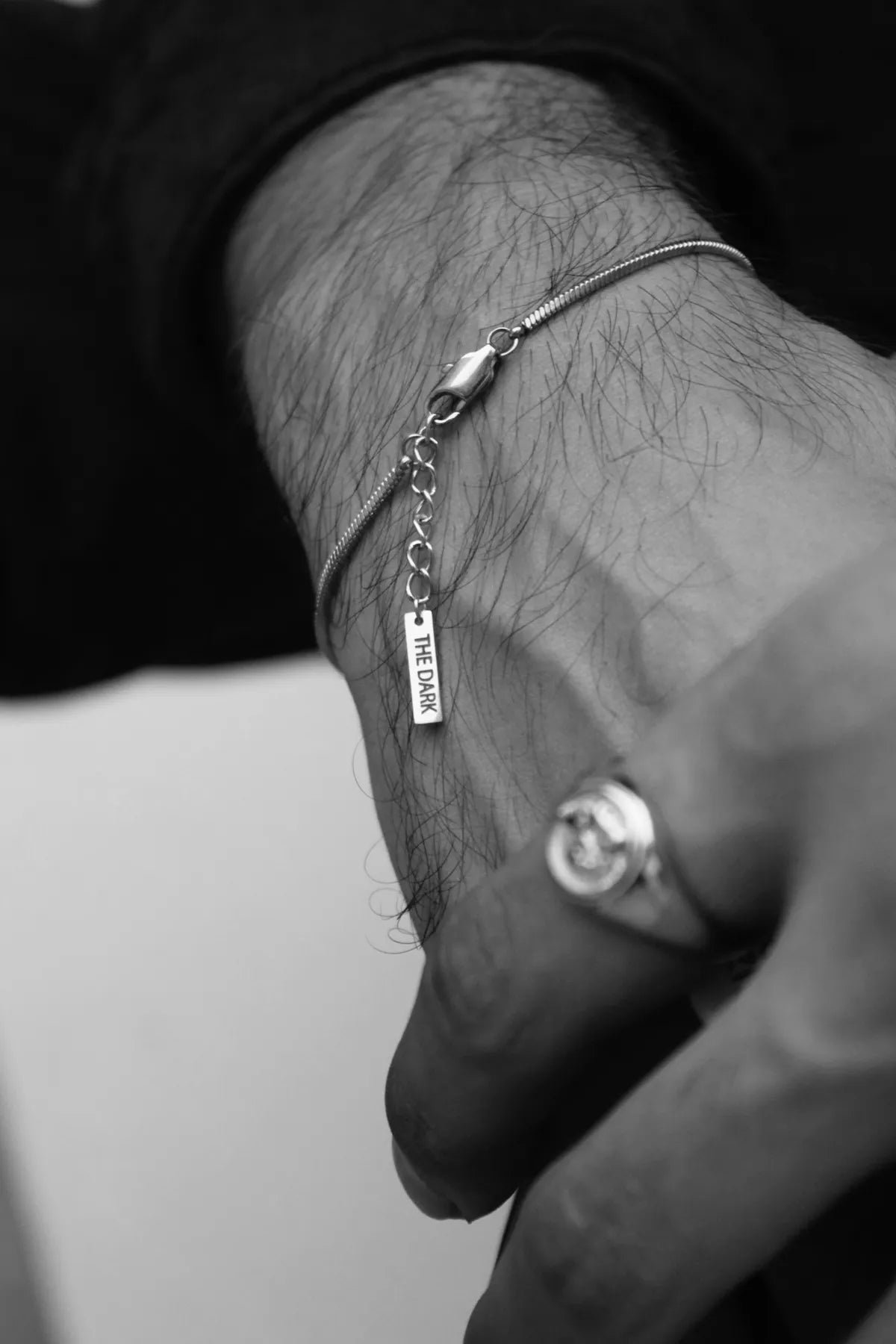 Men’s silver chain bracelet by The Dark, styled on wrist with ring with modern jewelry design in Pakistan