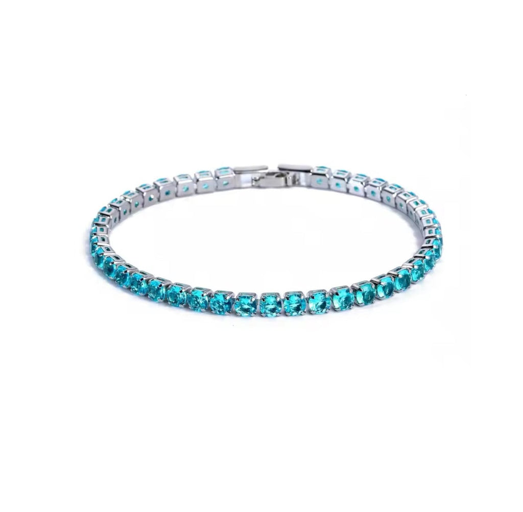 Light blue tennis bracelet displayed on a clean white background, featuring round-cut blue stones set in a polished silver frame  with a refined finish.